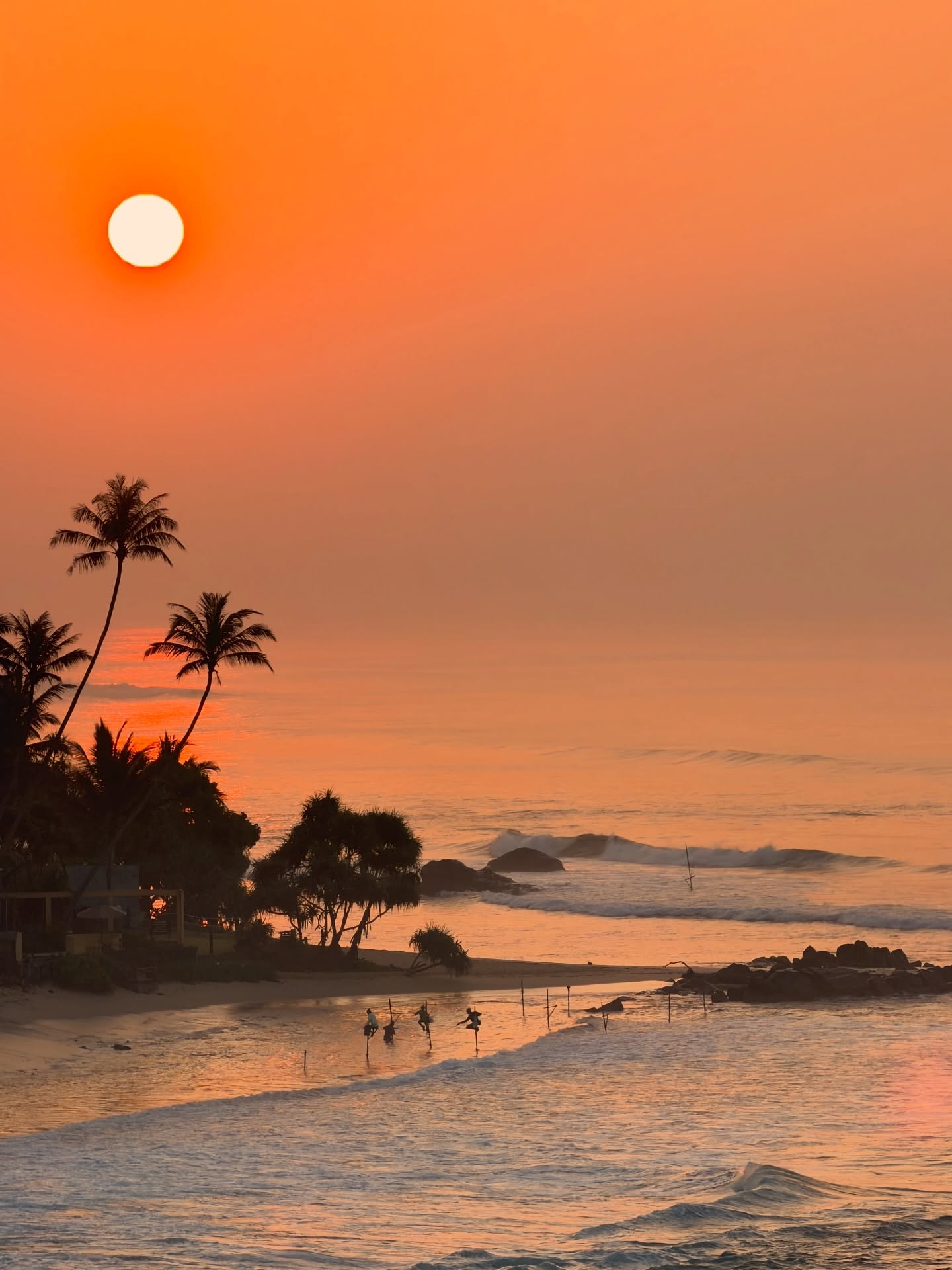 Sunset over the Sri Lankan coast with traditional stilt fishermen